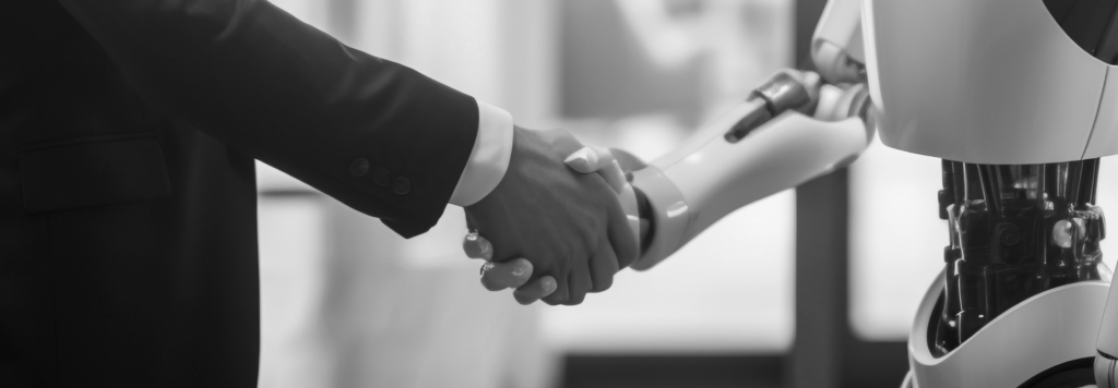 A businessperson in a black suit shaking hands with a humanoid robot, symbolising AI collaboration and automation in the modern workplace.
